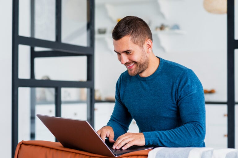 man smiling and using a laptop - Monday.com vs Jira