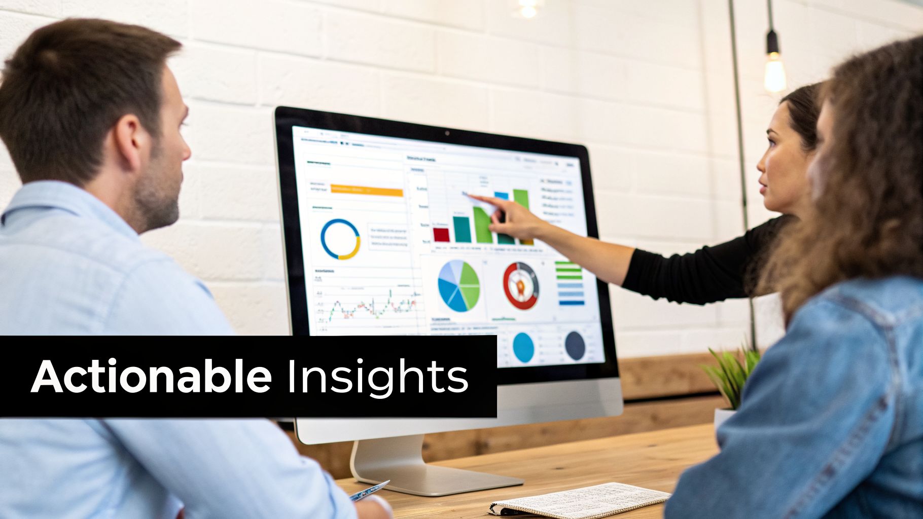 Three colleagues analyze data on a computer screen, discussing charts and graphs for insights.