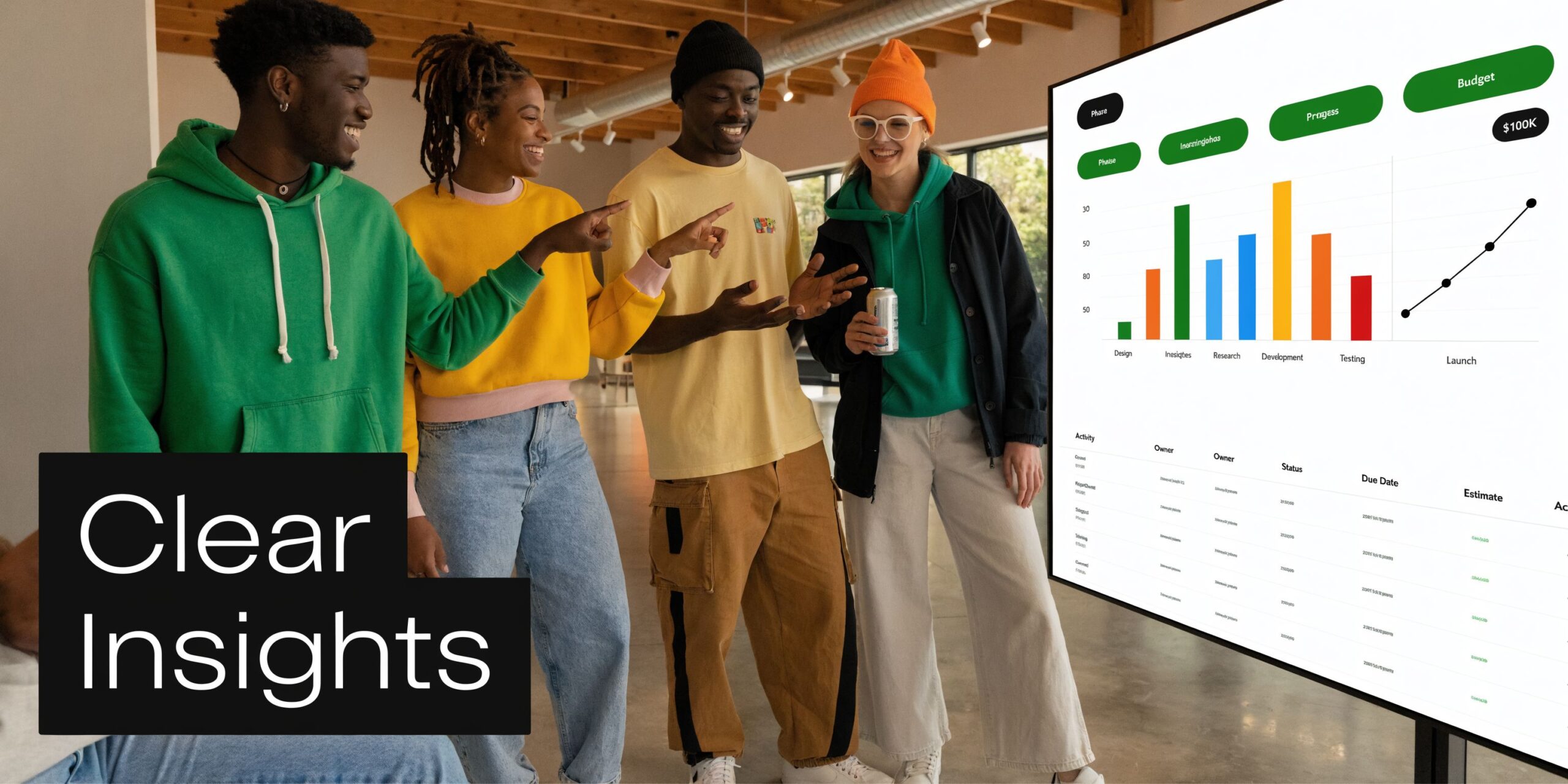 A diverse team of four colleagues stands in a modern office looking at data charts on screen.