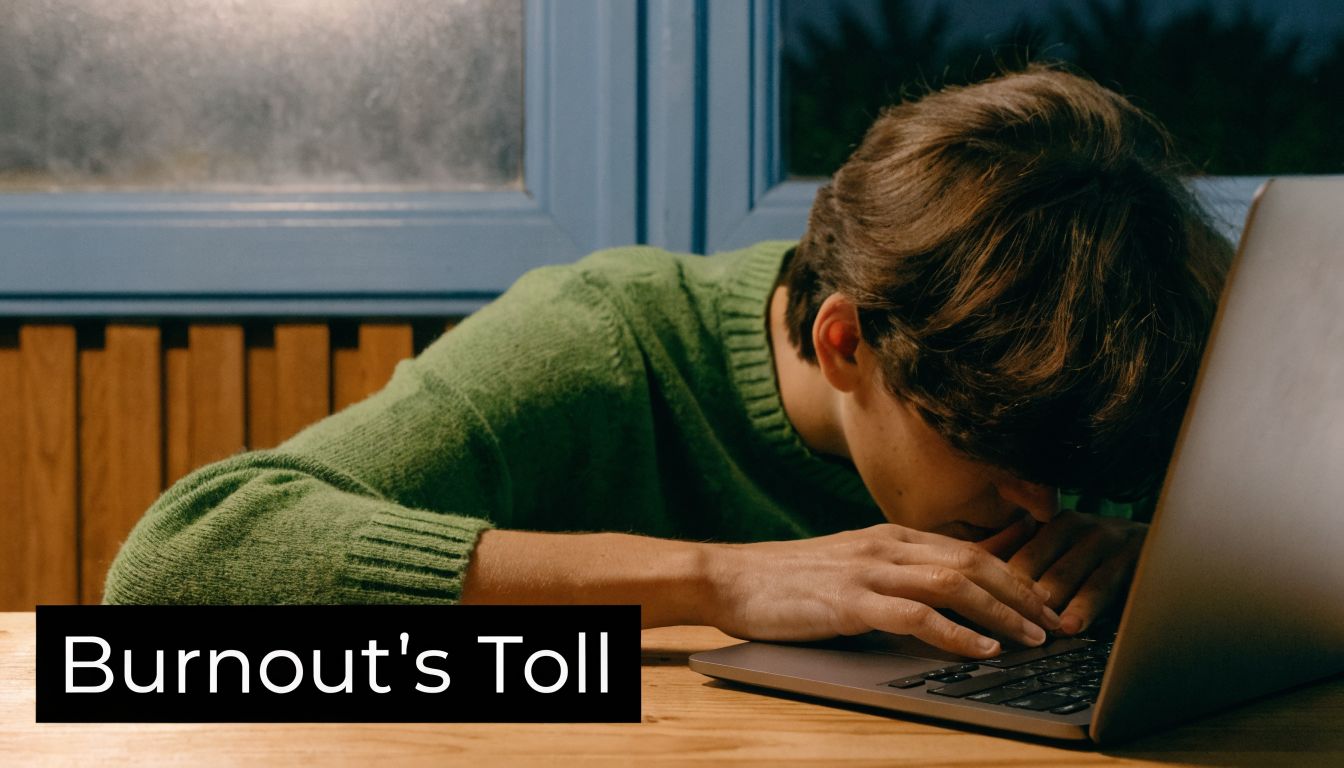 A person resting their head on a laptop in a dimly lit room representing workplace burnout