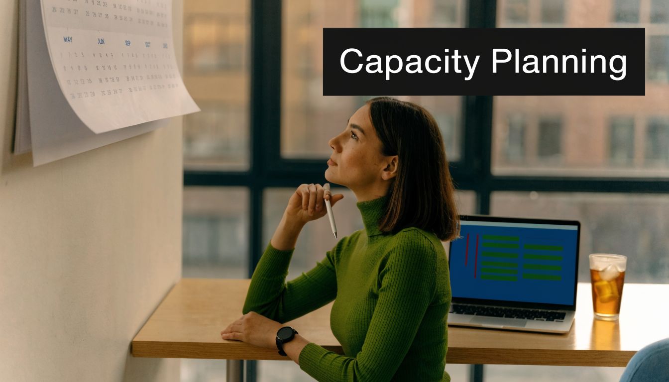 A professional woman in a green sweater thoughtfully looking at a wall calendar for capacity planning.