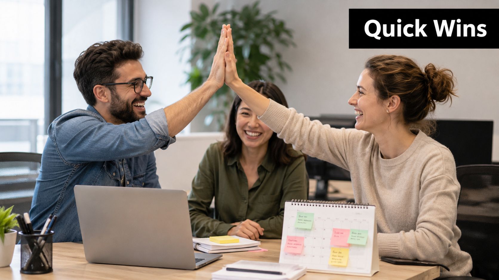 A diverse team of colleagues celebrating professional success with a high five in a modern office environment.