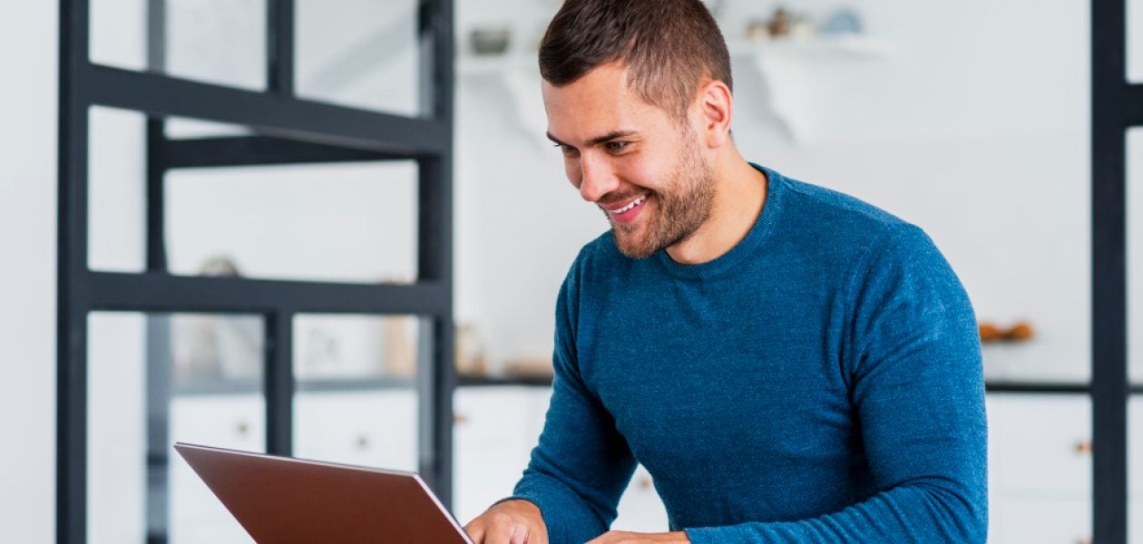 man smiling and using a laptop - Monday.com vs Jira